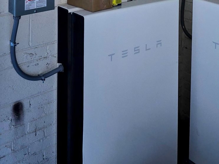 Tesla Powerwall battery storage system wired to subpanels in a basement