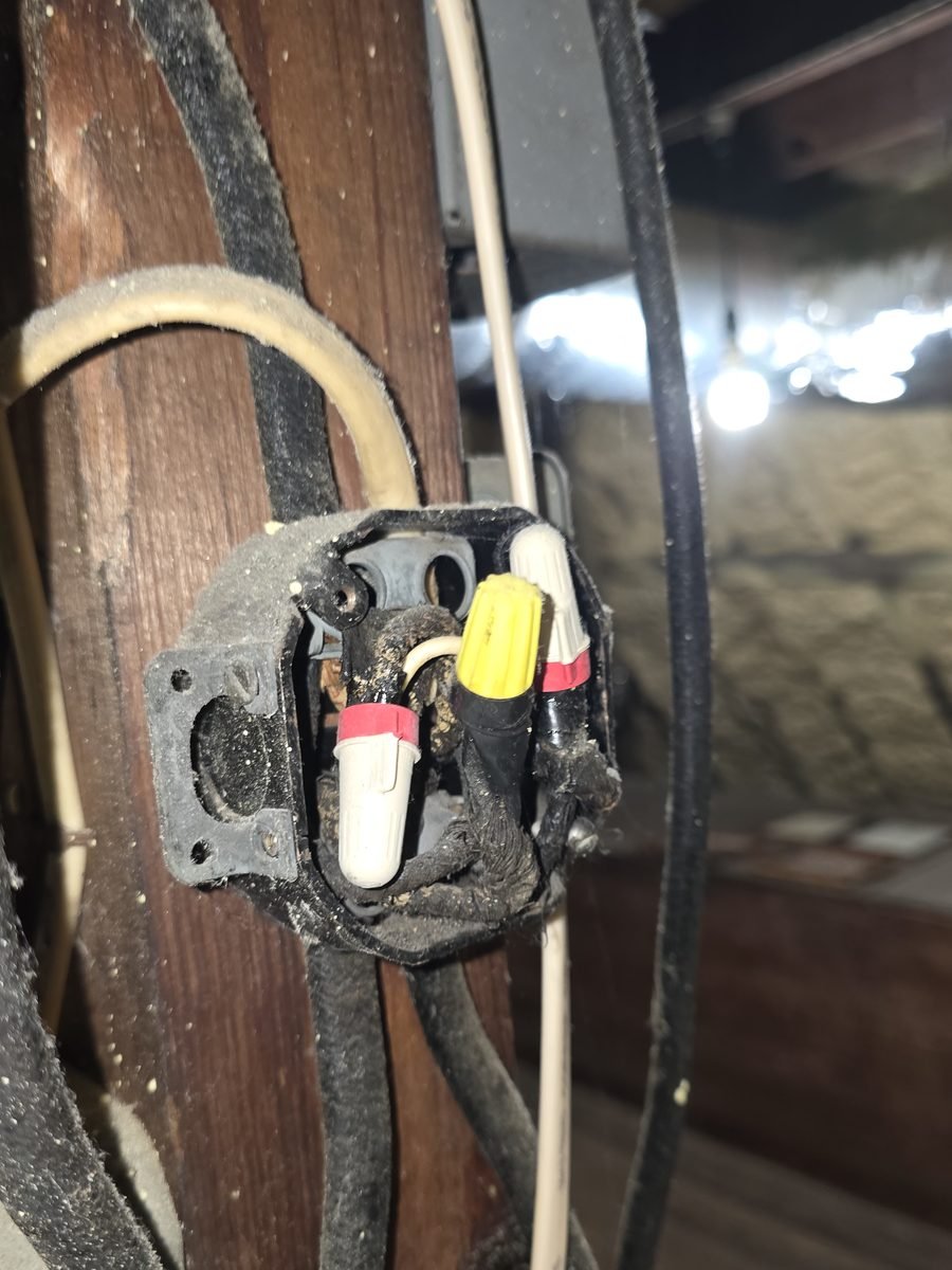 Old open junction box with cloth-covered cable mounted on a rough-sawn attic beam
