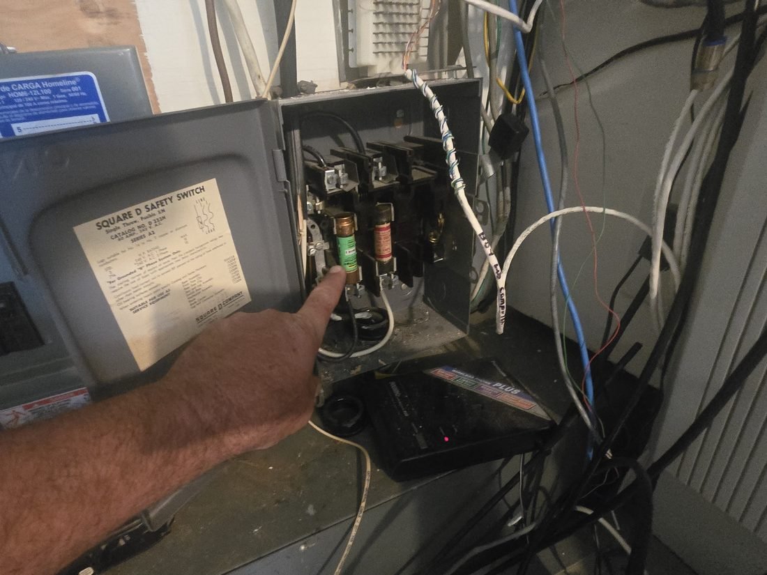 Technician pointing to a fuse inside a safety switch during an electrical inspection