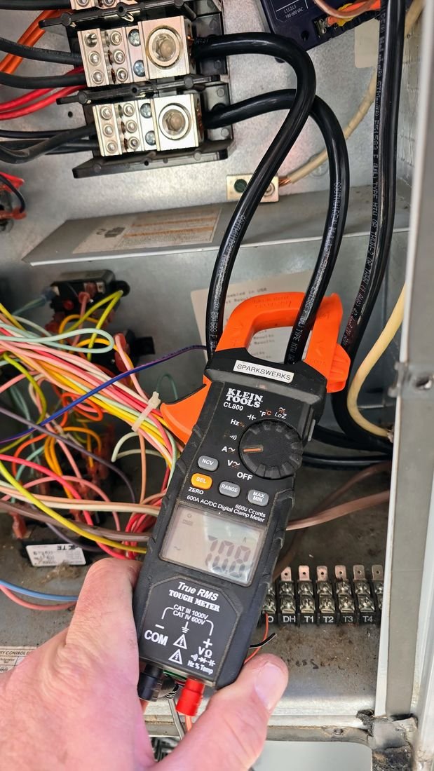 Sparkswerks technician using a clamp meter to troubleshoot an air handler circuit
